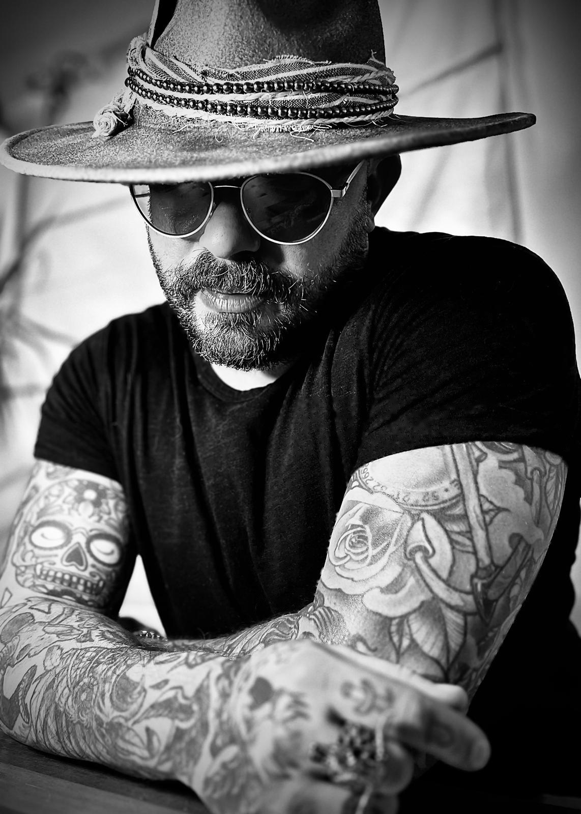 Black and white portrait of the coach in a wide-brimmed hat and sunglasses